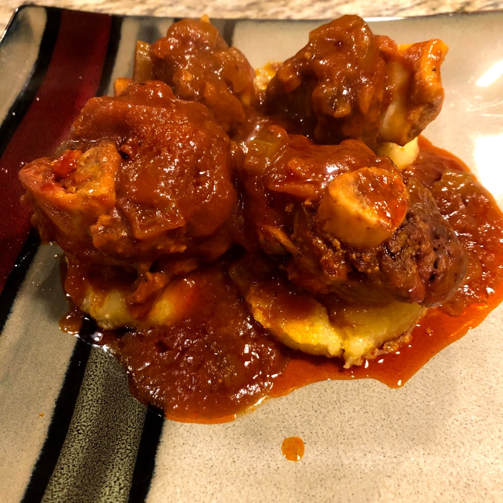 venison ossu bucco with a tomato sauce resting on discs of polenta