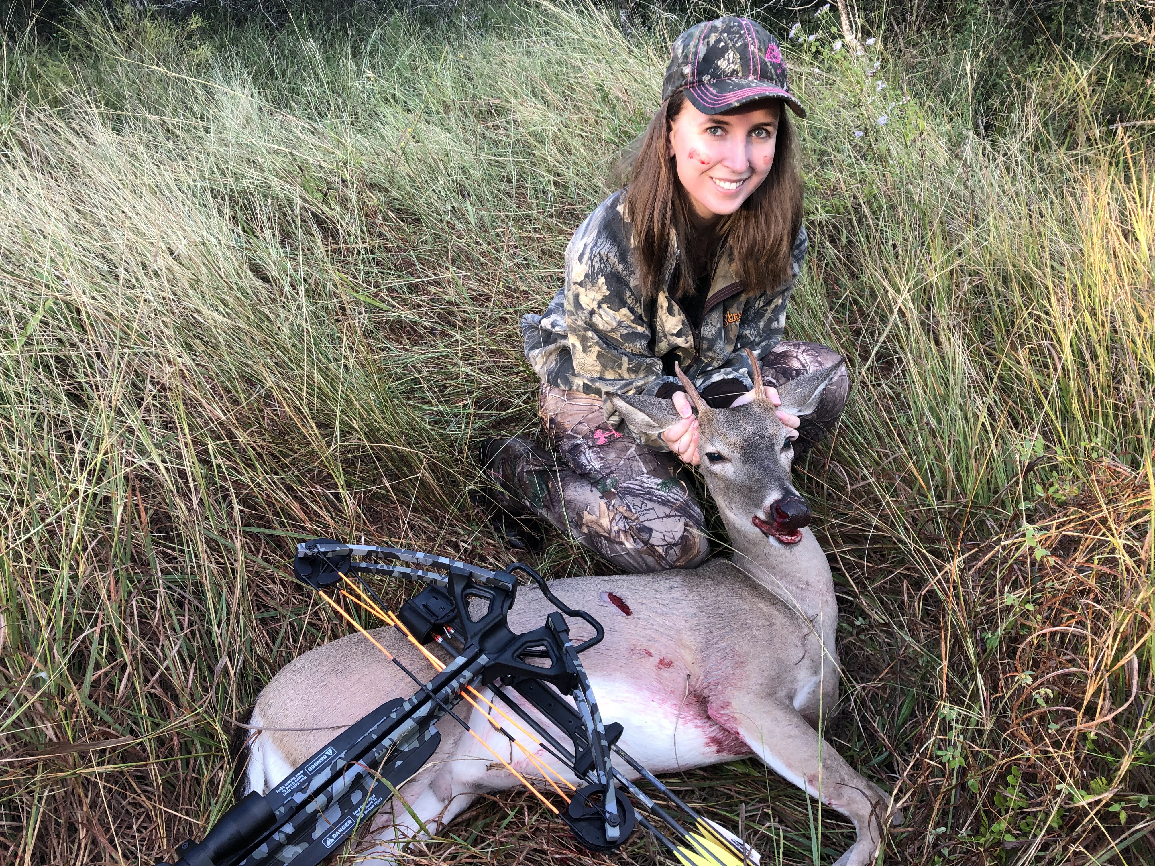 Jessica holding up her spike whitetail buck with a crossbow