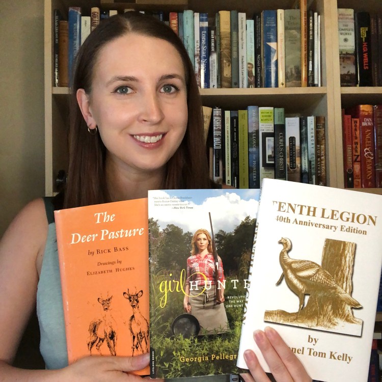 Girl holding three books in front of a bookshelf