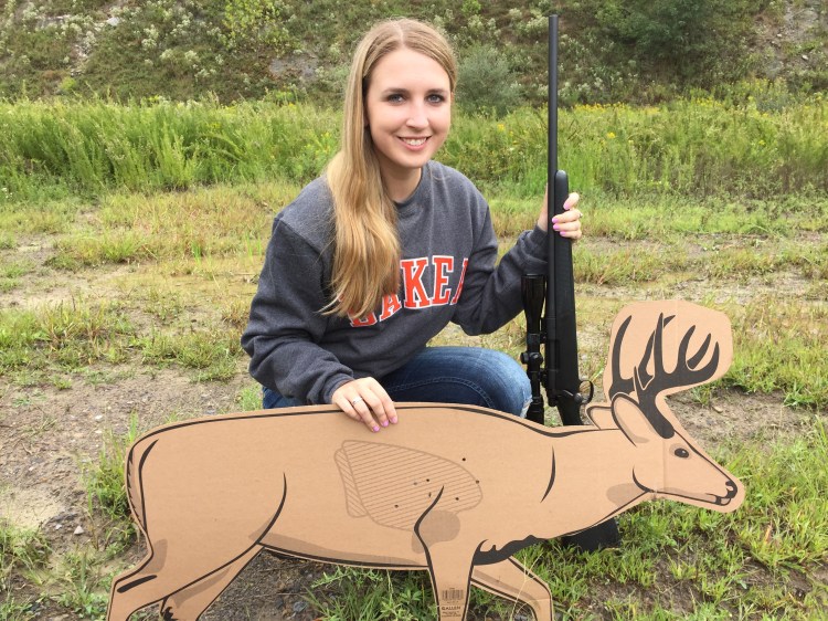 girl holding rifle and cardboard deer in a field