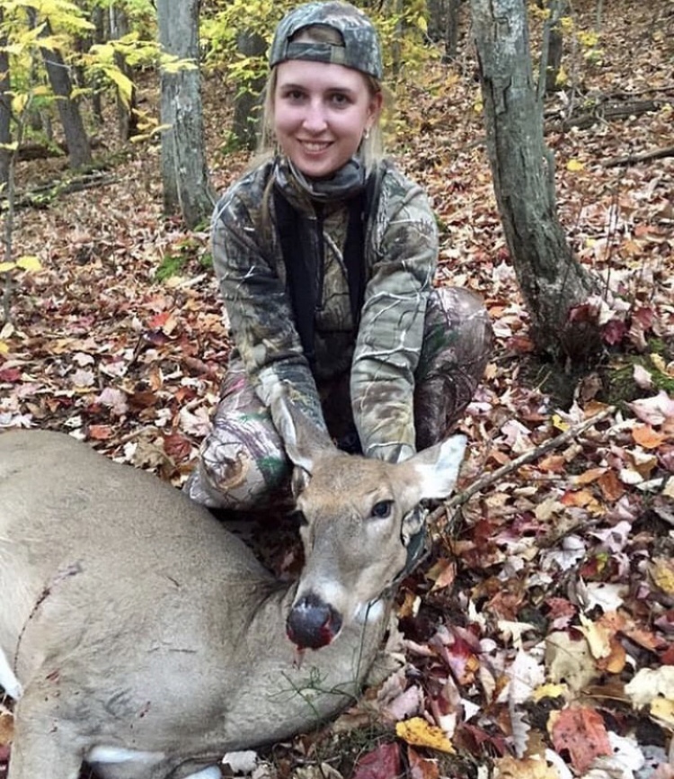 Jessica in the woods holding up a doe