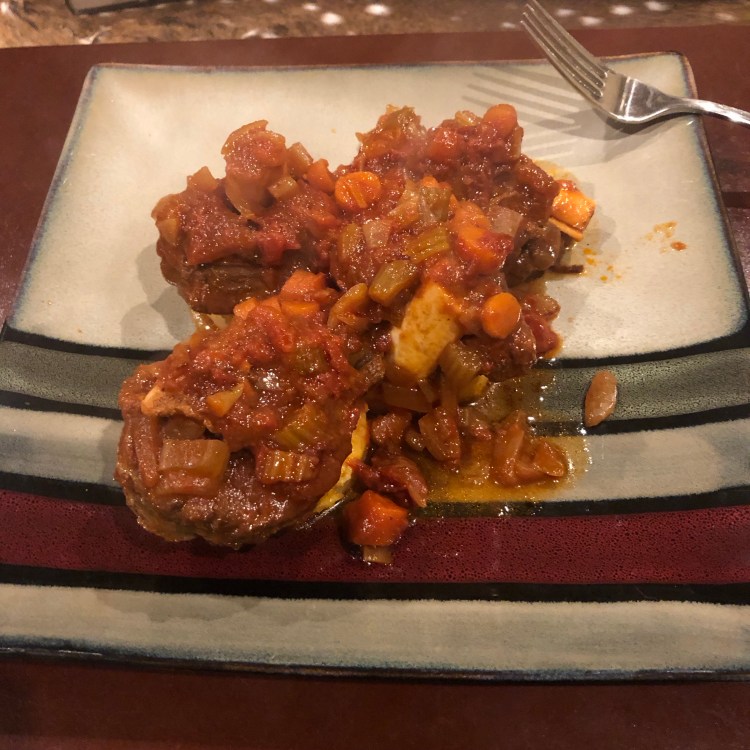 venison osso buco with a tomato and vegetable sauce on a bed of lightly fried polenta