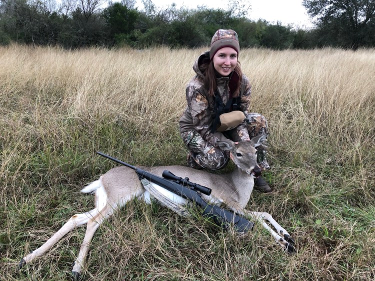jessica holding up whitetail doe with rifle in a field